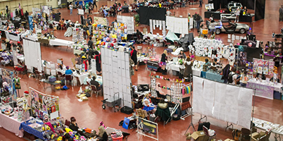 an overhead view of the artist alley at AnimeCON. There are many booths and people scattered about.