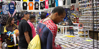 a group of people browsing a figure collection at a booth at AnimeCON.