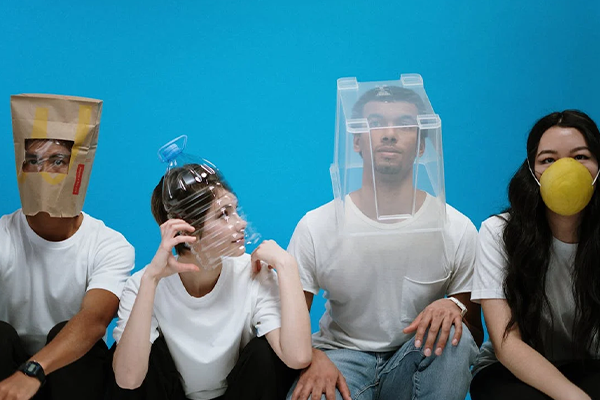 four people in a line with various objects covering their faces