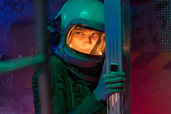 Main actress of Infinite Possibilities stares at the camera in a space suit