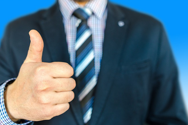 a man in a suit, with only a thumbs up in focus