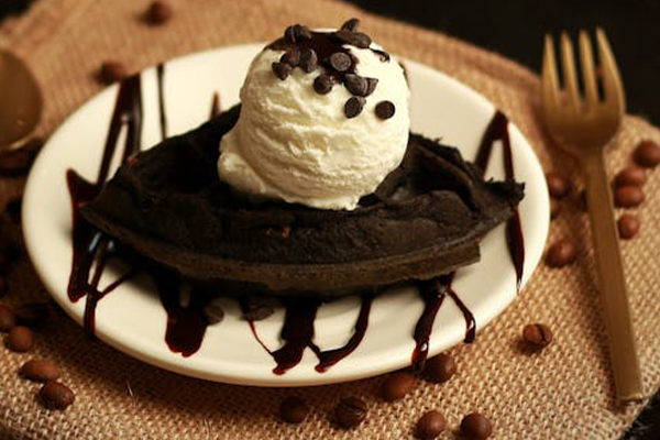 a scoop of icecream on a brownie slice, next to a fork and spoon